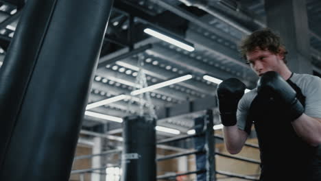 agitated fighter working on blows in fitness center. sportsman training kicks