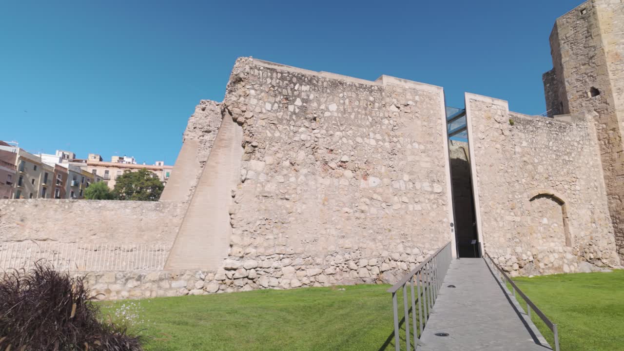Ancient stone walls and entrance of The Monges Tower under clear blue skies in Tarragona Spain
