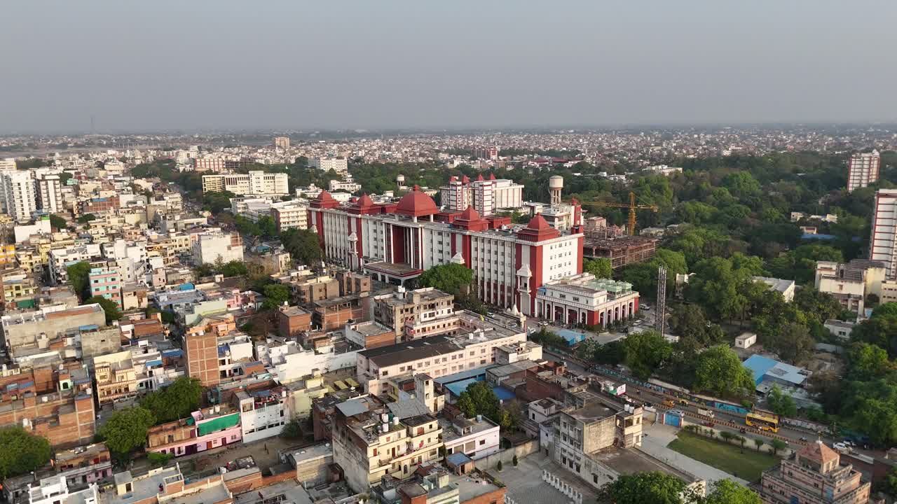 High-altitude view of Varanasi's riverfront, where colorful boats float lazily on the Ganges, framed by ancient stone steps and bustling marketplaces.