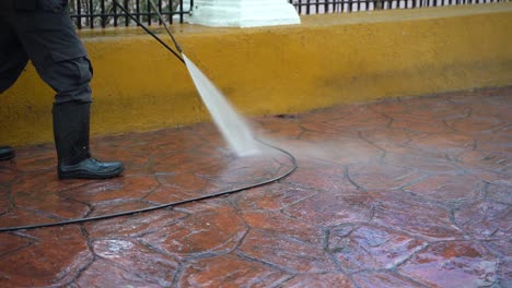 Slow-motion-closeup-of-a-person-power-washing-the-paved-sidewalk-in-a-park