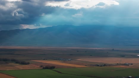 Dramatic-drone-shot-panning-to-the-left-of-sunlight-coming-through-storm-clouds