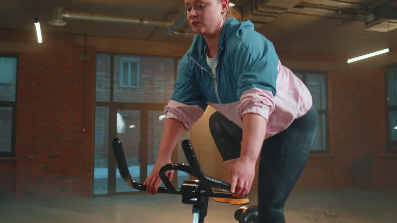 Woman performs aerobic endurance training workout cardio routine on the simulators cycle training