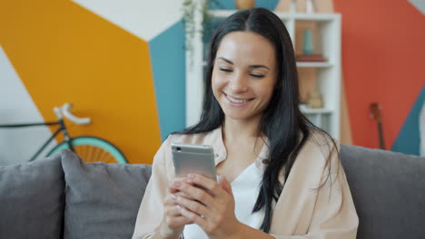 mujer usando un teléfono inteligente en un sofá