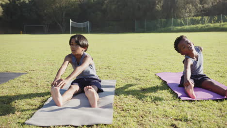 stretching on yoga mats, children exercising outdoors during school pe class