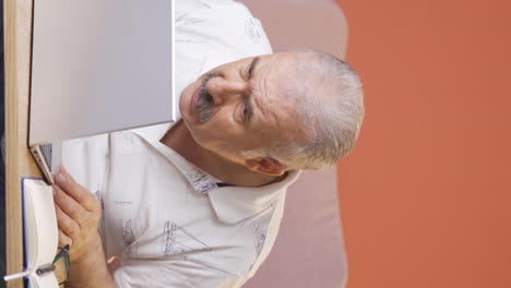 Vertical-video-of-Old-man-looking-at-laptop-in-amazement.