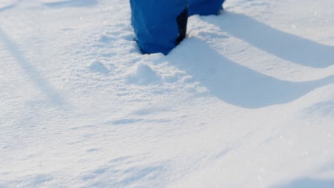 person walks towards camera through fresh, deep snow, slow motion, close up on feet.