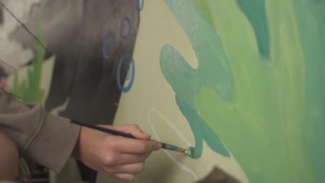 person painting a mural painting on wall with a paint brush creating art