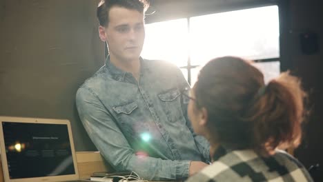 two casual people, young guy and a girl, talking to each other, indoors.