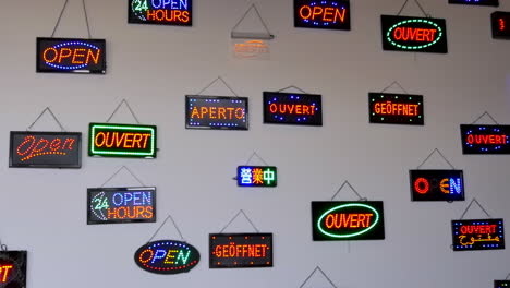 colorful neon "open" signs in multiple languages hanging on a white wall, creating a vibrant and multicultural visual mosaic