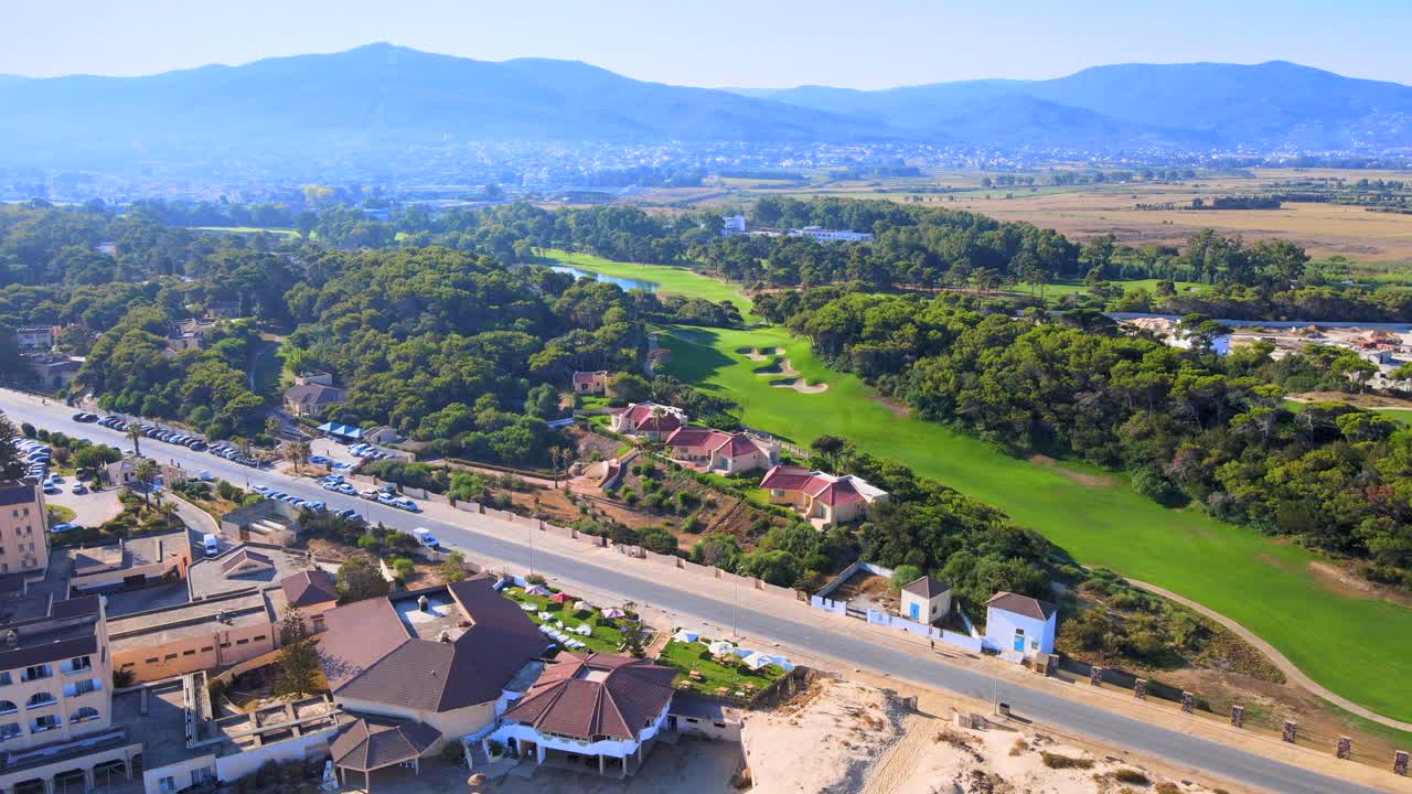 This 4K aerial stock footage captures a lush green golf course in the beautiful location of Tabarka,The scenic golf course is filled with many trees and houses, creating an idyllic atmosphere