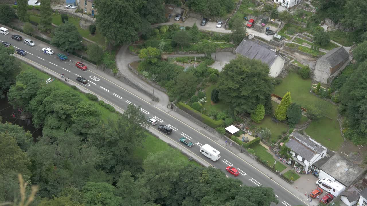 Pedestrians and traffic in riverside village on a valley.