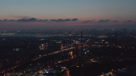 Istanbul-at-Night-with-City-Lights-and-Turkish-Flag-waving,-Aerial-perspective