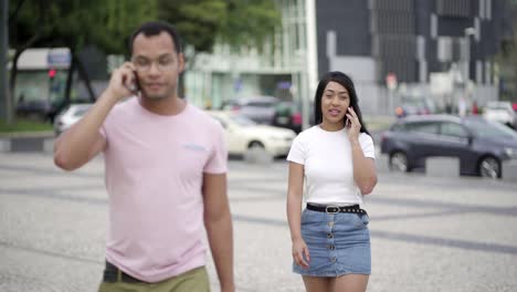 cheerful young man and woman talking on smartphones