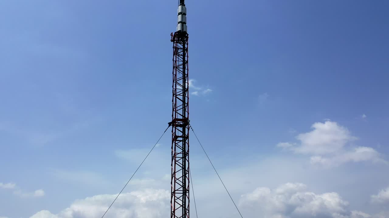 vista aérea de arriba hacia abajo de un relé de microondas o de una torre de radio y celular contra un fondo de cielo y nubes