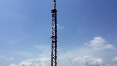 vista aérea de arriba hacia abajo de un relé de microondas o de una torre de radio y celular contra un fondo de cielo y nubes