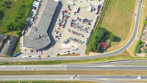 aerial view of the logistics park with warehouse, loading hub and many semi trucks with cargo trailers standing at the ramps for load unload goods at sunset