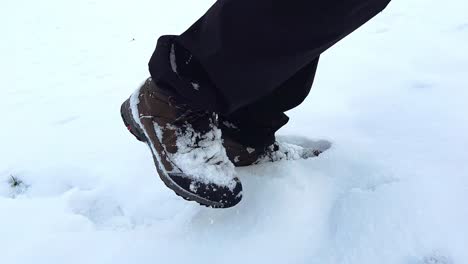 medium close-up of male hiker walking through powdery snow up a hill