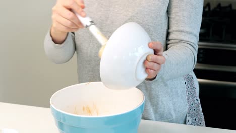 Woman-adding-ingredients-to-bowl-for-baking