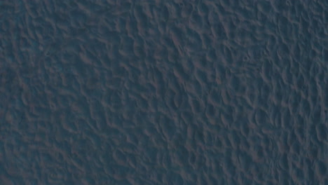 4k top down aerial shot of abstract white sand on a beach during sunet