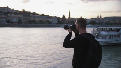 photographer taking pictures of the budapest skyline next to the donau river while sunset