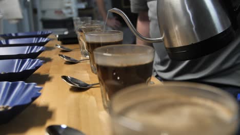 hot steamy water is poured for coffee cupping taste test, slow motion close up