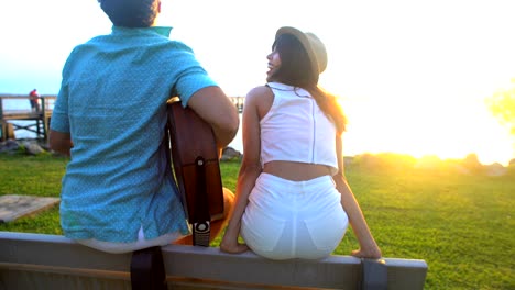 multi ethnic couple playing guitar on beach vacation