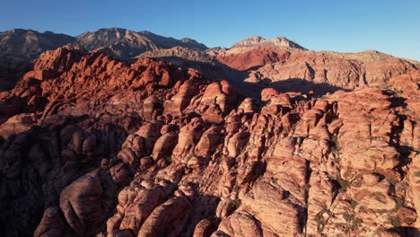 aerial footage of red rock mountains canyon formation in las vegas , drone close up of scenic landscape against blue clear sky