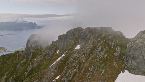 djevelporten norway aerial v6 high altitude drone flyover mountain ridges, fly through thick layer of fog reveals svolvær airport and beautiful fjord landscape - shot with mavic 3 cine - june 2022