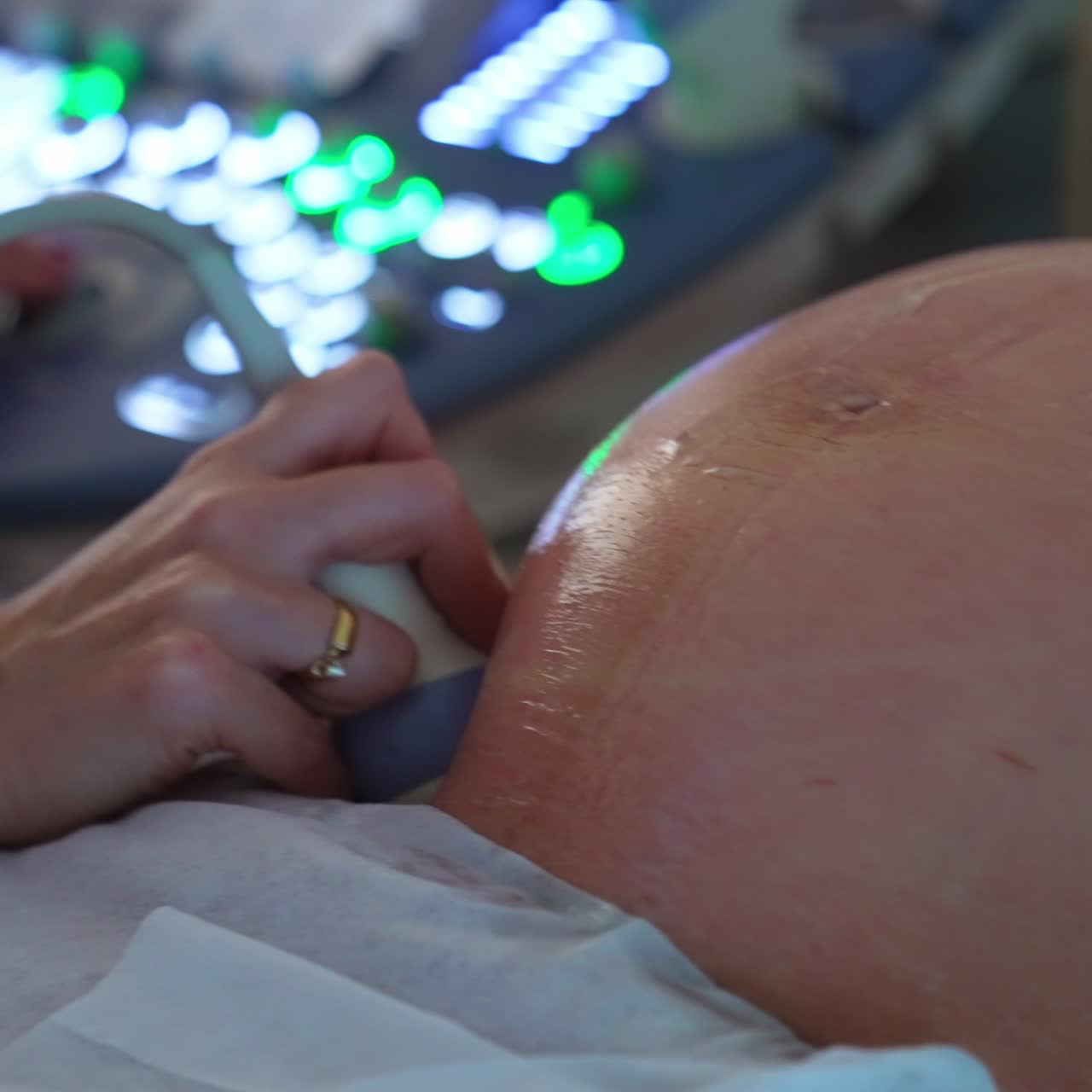 Ecografia per una donna incinta. Grande addome rotondo esaminato dalla sonda ecografica nella mano del medico. Primo piano