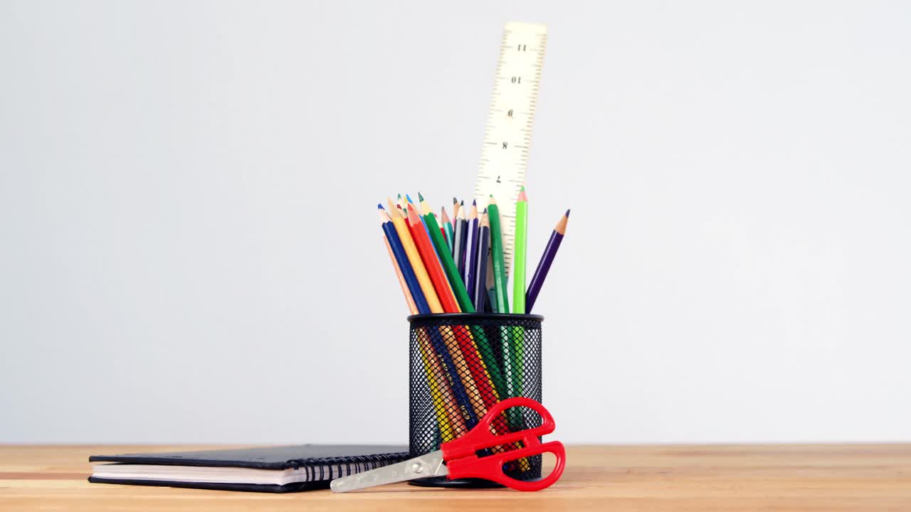 primer plano del soporte de la pluma con lápiz de color, diario y tijeras