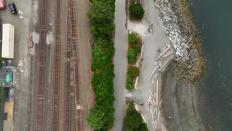 Rising-aerial-view-of-the-Elliott-Bay-Trail-in-downtown-Seattle-surrounded-by-train-tracks-and-the-waterfront