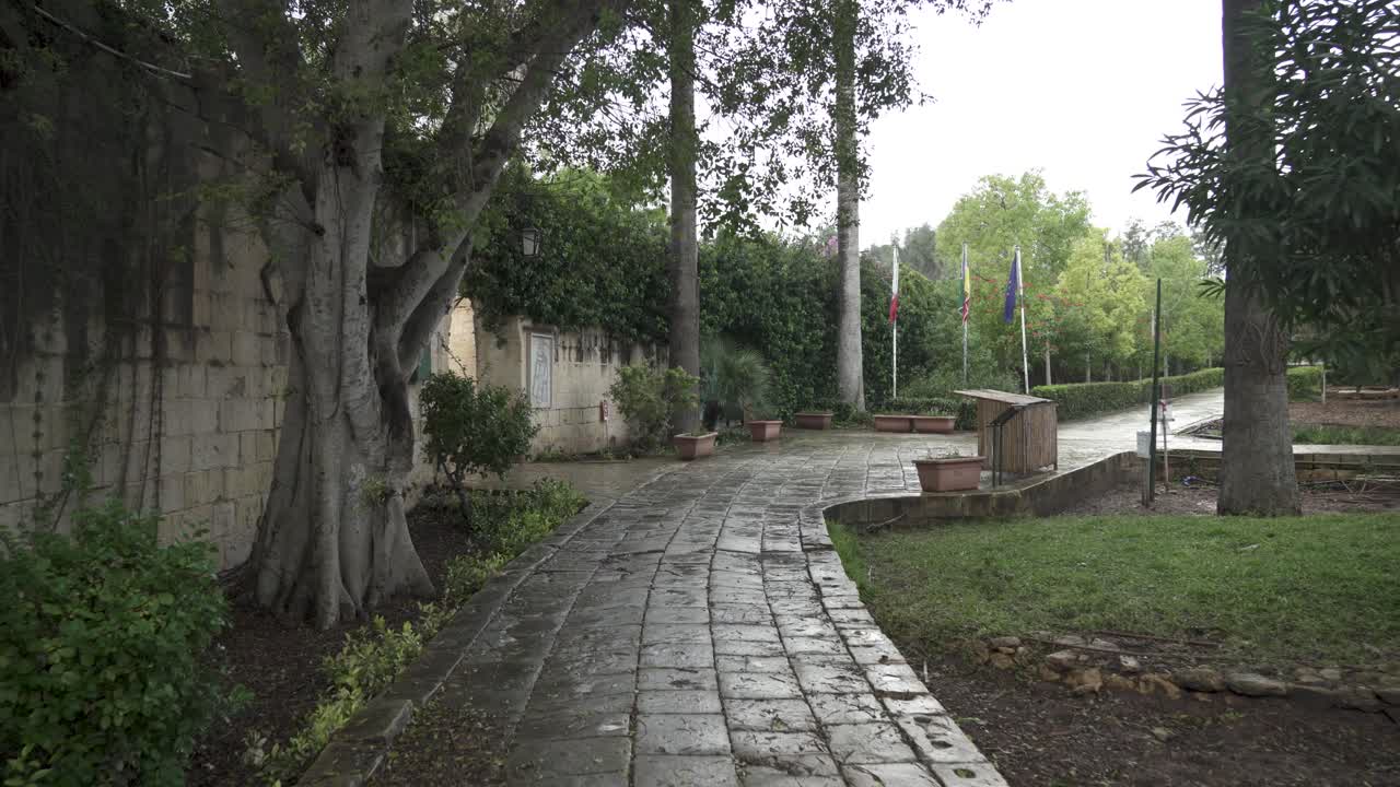 Wet Stone Path Leading Around San Anton Gardens on a Bloomy Day