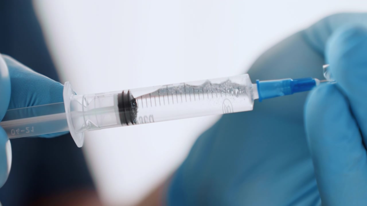 Medicinsk sprøjteundersøgelse. Sundhedspersonale undersøger sprøjte nøje for luftbobler. Medicinsk fagperson kontrollerer omhyggeligt sprøjten for at sikre, at der ikke er luftbobler før patientinjektion.
