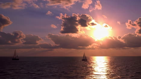 sailboats at sunset through storm clouds