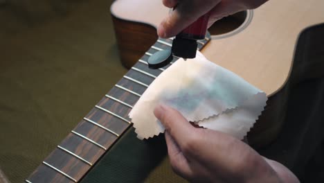 man putting lemon oil cleaner conditioner onto a cloth for acoustic guitar fingerboard maintenance and cleaning