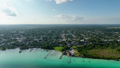 Vista-Aérea-Lejos-Del-Pueblo-De-Bacalar,-En-El-Soleado-México---Tire-Hacia-Atrás,-Tiro-De-Drones