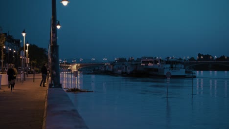 Night riverside scene with boats and streetlights reflecting on water during the Budapest flood