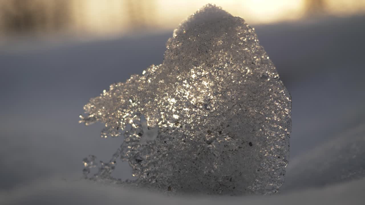Il ghiaccio si forma con dettagli scintillanti sotto il sole sulla neve durante una mattina d'inverno.