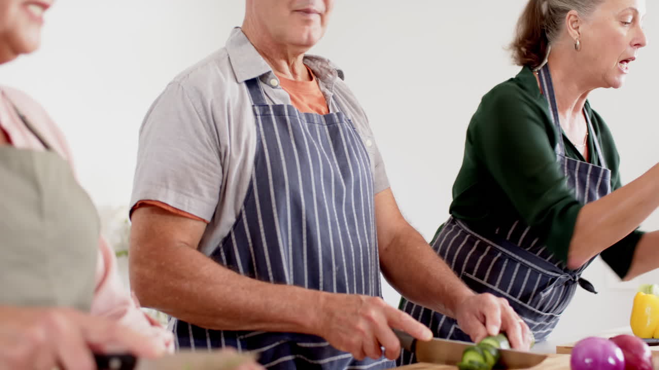 Senior man chopping vegetables on cutting board, wearing apron in kitchen
