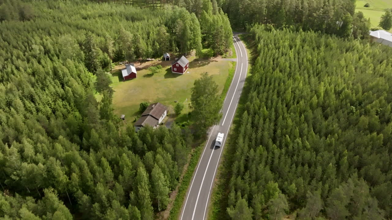 High angle aerial tracking a camper van on a rural road in Finland, summer day