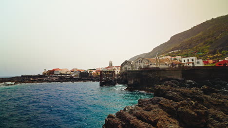 panoramic view of the small town of garachico in tenerife, canary islands, spain. view of the turquoise sea and the black volcanic rocky coastline surrounding the local town.