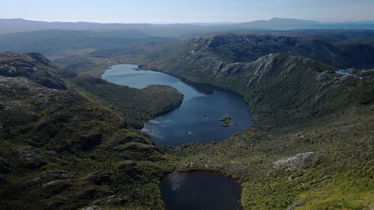 vista aérea de arriba de un lago con colinas y montañas en el fondo