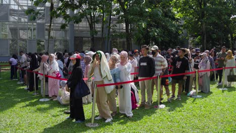 people standing in line at an outdoor event in bogor on a sunny day