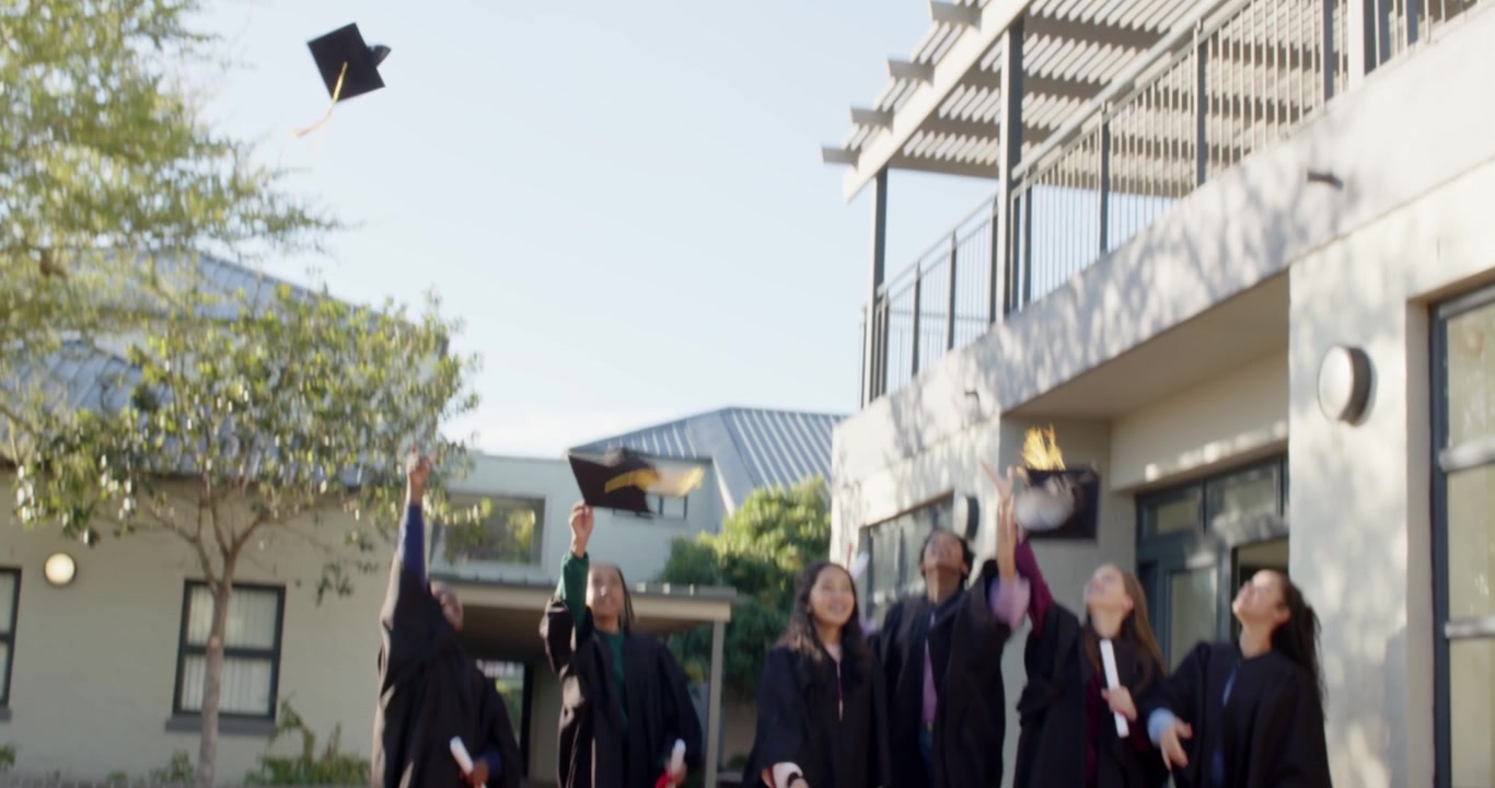Compañeros de clase diversos celebrando la graduación con togas negras, sosteniendo diplomas en el patio y lanzando birretes.