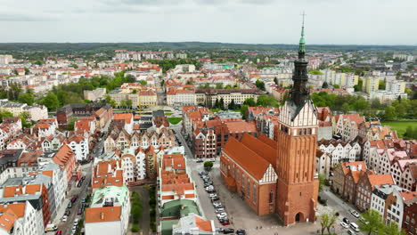 vista aérea de elbląg mostrando el centro histórico de la ciudad con una gran iglesia y una mezcla de edificios viejos y nuevos que se extienden hacia el horizonte