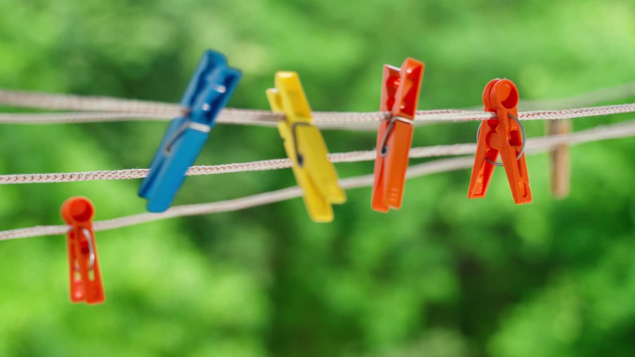 Multi-colored clothespins sway in the wind on the clothesline.