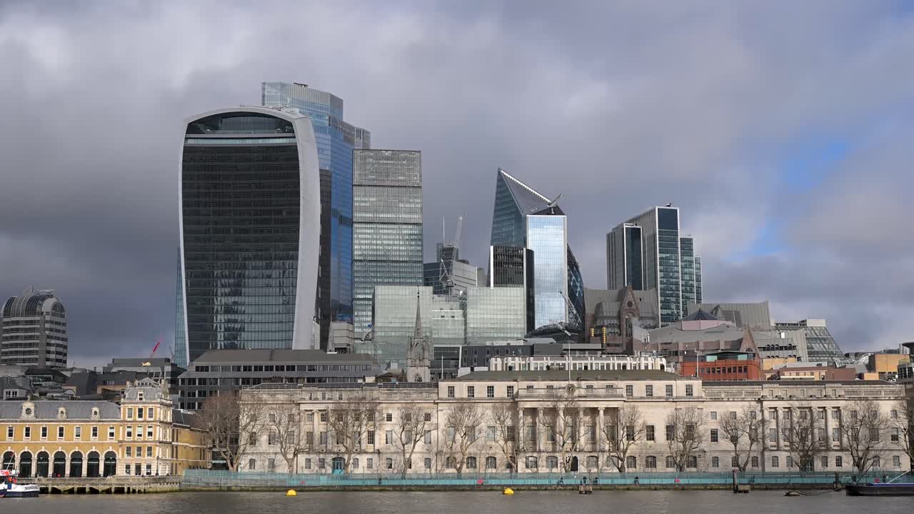 Una prospettiva panoramica serale dello skyline del distretto finanziario della City di Londra, con grattacieli illuminati che si riflettono sul fiume Tamigi, visti dalla South Bank.