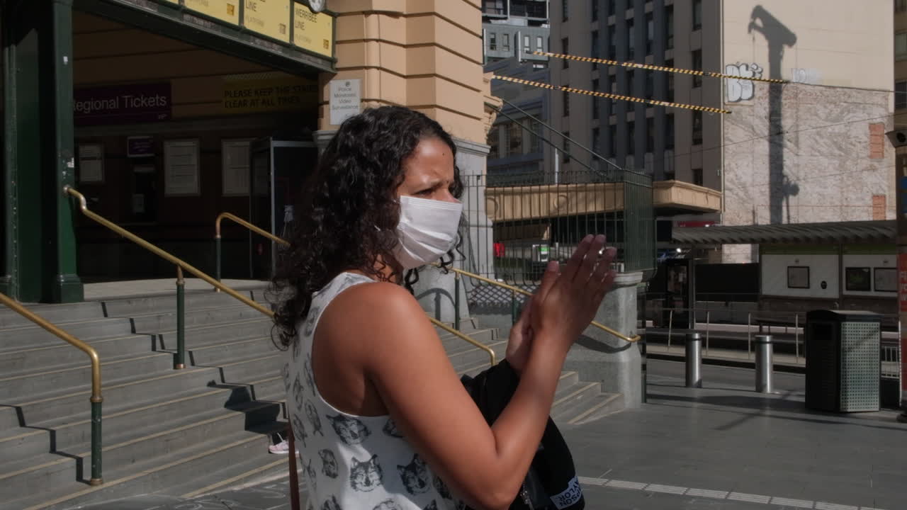 Woman wearing mask applying sanitiser during world covid19 outbreak, Melbourne Australia