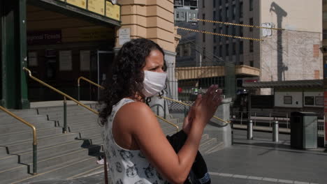 woman wearing mask applying sanitiser during world covid19 outbreak, melbourne australia