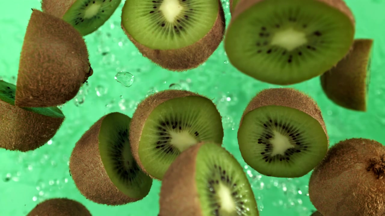 Súper cámara lenta de kiwis frescos cayendo con salpicaduras de agua